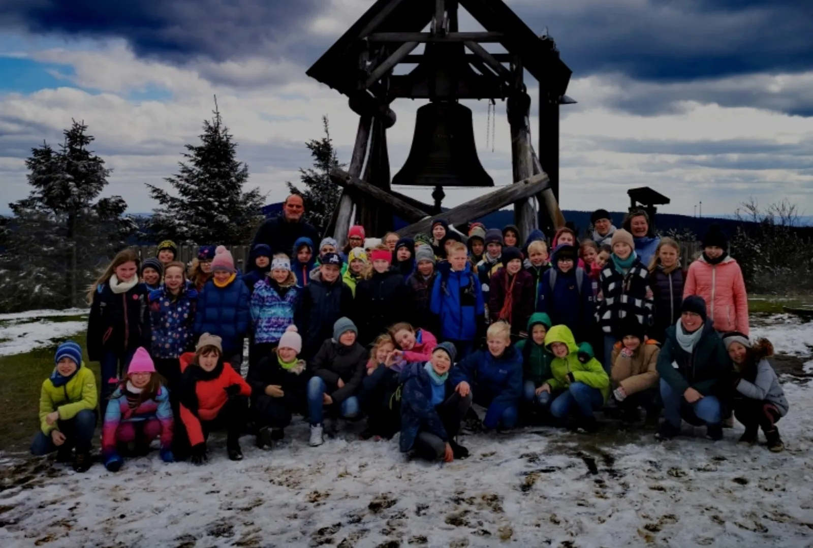 Die Reisegruppe der vierten Klassen vor der Glocke auf dem verschneiten Fichtelberg.